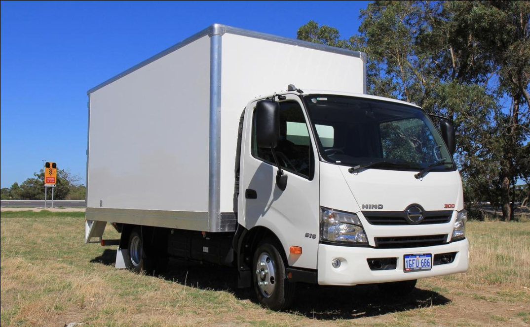 White Hino 300 light box truck parked on grass