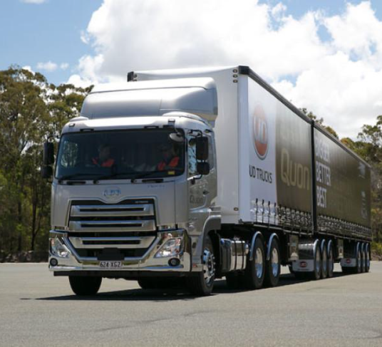 Silver UD Trucks prime mover hauling two curtain-side trailers